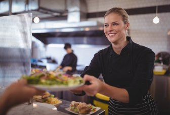 photo kitchen staff serving food on plate to customer