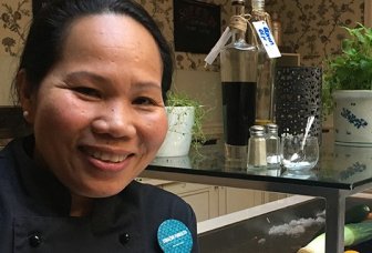 Photo of Chef Corazon Furuseth with herbs and greens in the background.